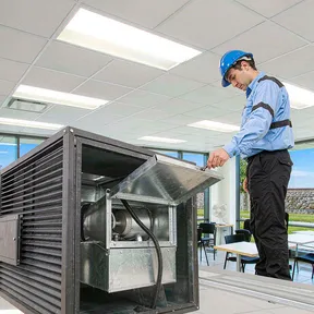 Technician inspecting Deiiang backdraft dampers in a commercial building exhaust system