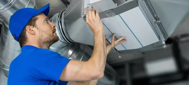 Technician checking a damper access panel on rectangular ductwork Technician checking a damper access panel on rectangular ductwork