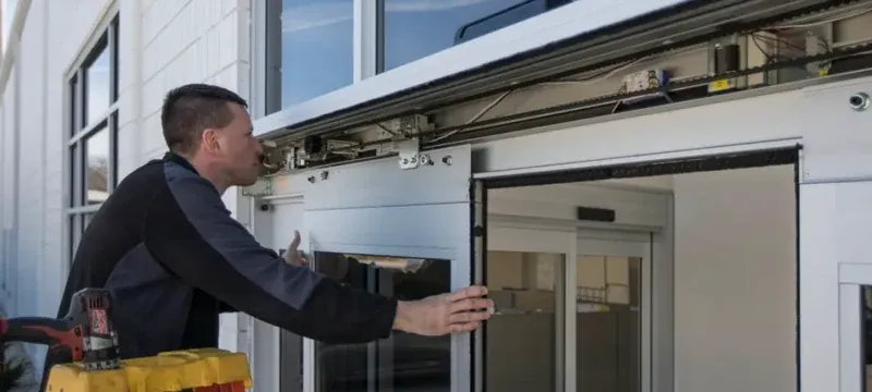 Technician servicing the operator and track of an automatic sliding door Technician servicing the operator and track of an automatic sliding door