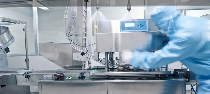 Aseptic filling room with stainless equipment and an operator in a cleanroom coverall