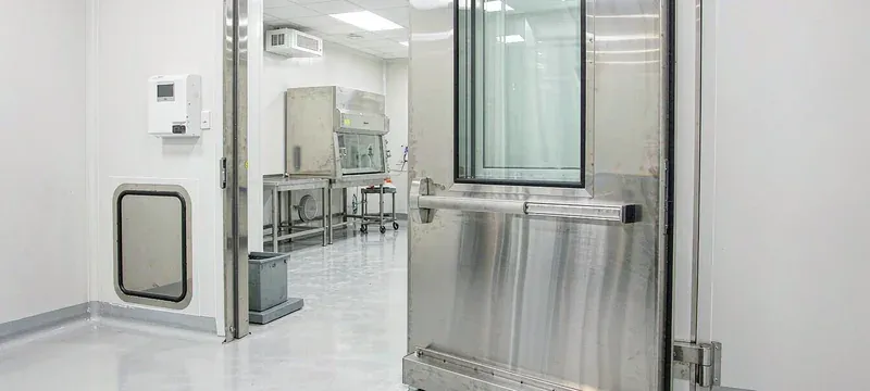 Stainless steel cleanroom door ajar at a USP 797 compounding pharmacy ante-room with a pass-through hatch Stainless steel cleanroom door ajar at a USP 797 compounding pharmacy ante-room with a pass-through hatch